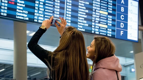 Dos turistas observan la pantalla de salidas del aeropuerto