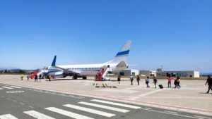 Avión en pista con pasajeros desembarcando, día soleado