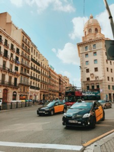 Taxis negros y amarillos circulando en Barcelona junto a un bus turístico.