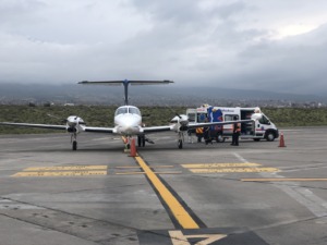 Avión bimotor en pista junto a ambulancia en aeropuerto