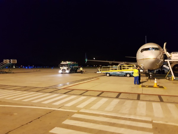 Avión en plataforma iluminada de noche, personal de apoyo presente