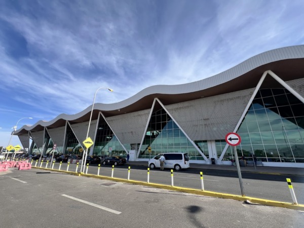 Fachada del aeropuerto con señal de tránsito y vehículos