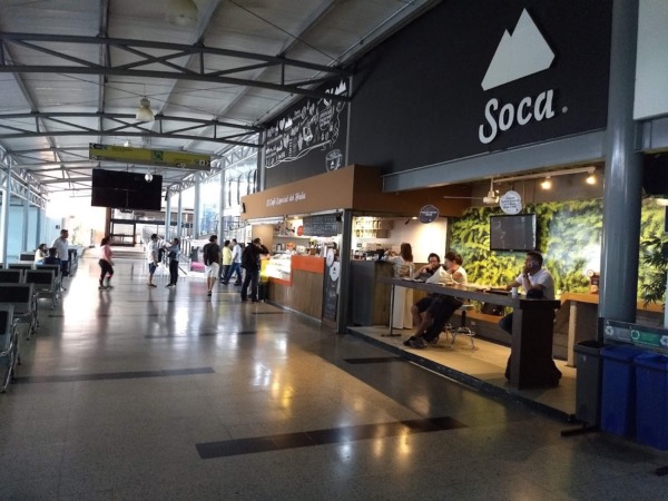 Interior del aeropuerto con personas y cafetería
