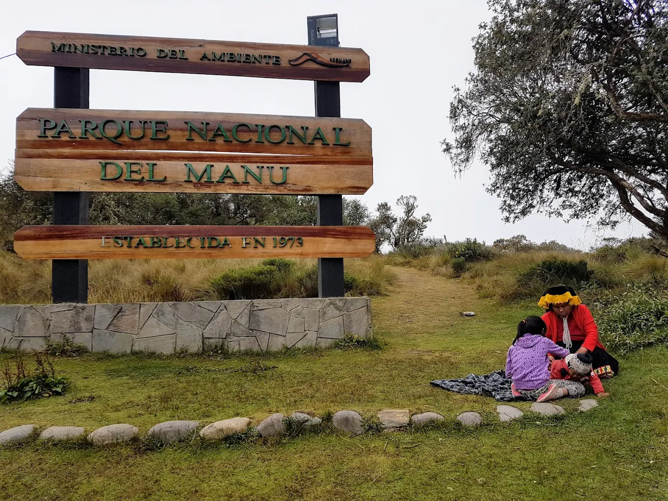 Visitantes descansan cerca del letrero del Parque Nacional…
