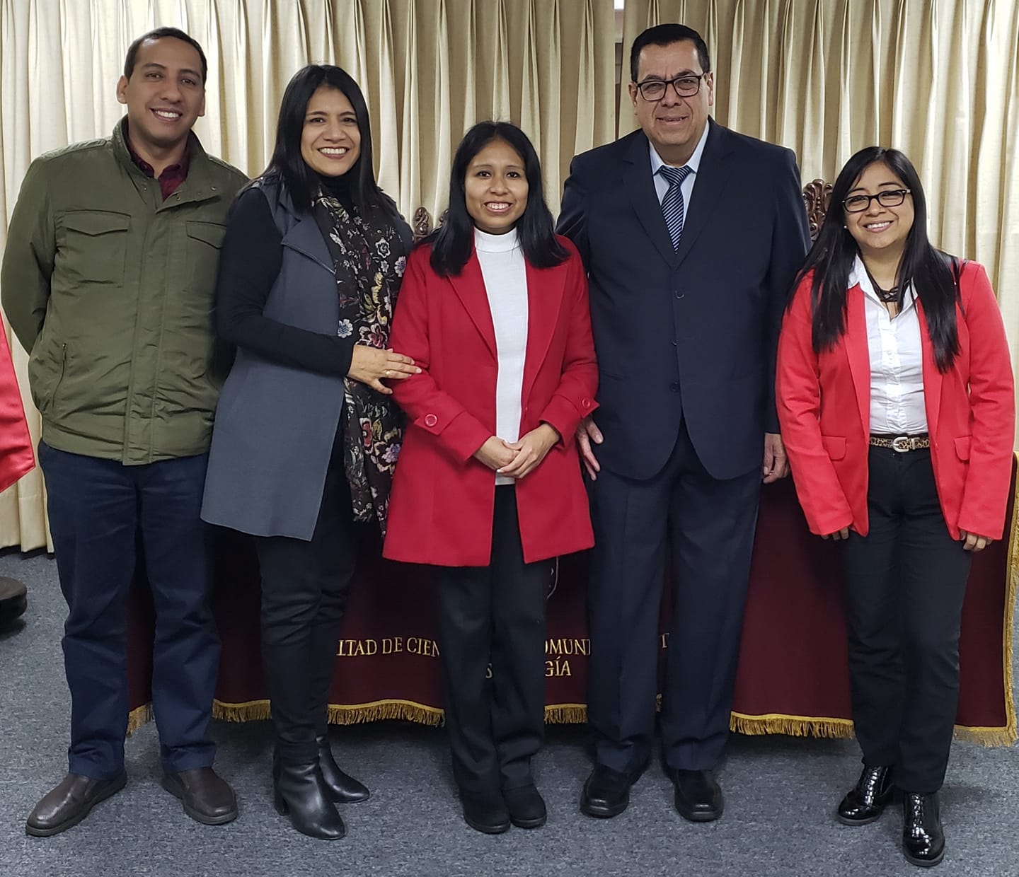 Grupo sonriente posa frente a cortinas doradas