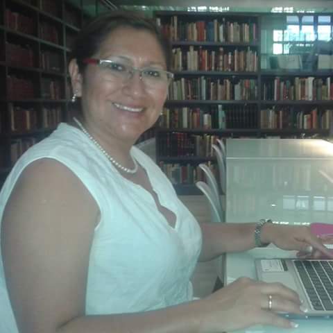 Investigadora sonríe frente a estantería llena de libros