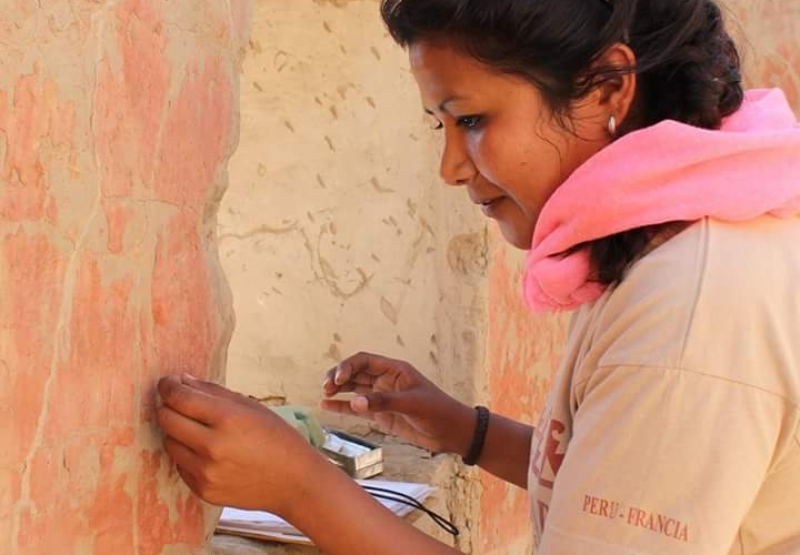 Arqueóloga examina mural antiguo con meticulosidad