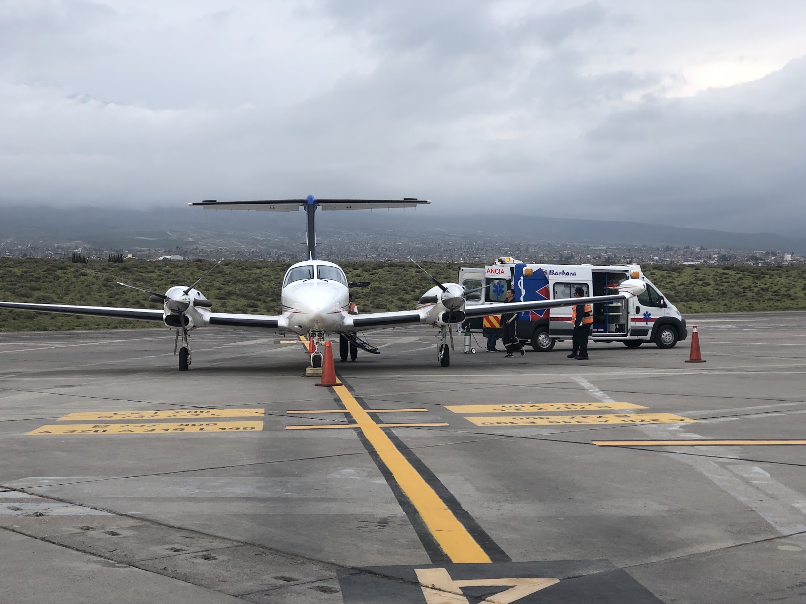 Avión bimotor en pista con ambulancia cercana