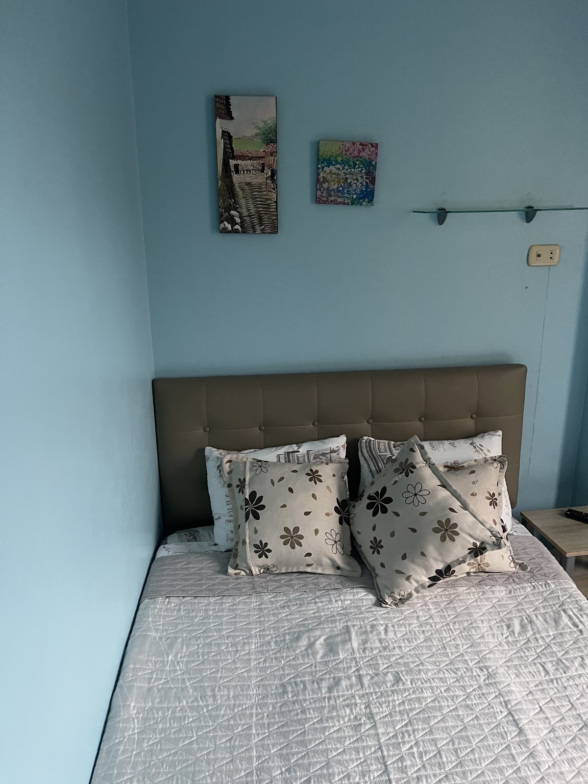 Habitación de hotel con cama matrimonial y almohadas florales